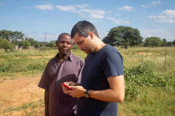 istock african village, old entrepreneur man together with a ngo social worker using a phone learning new skills for a small business 1998565963