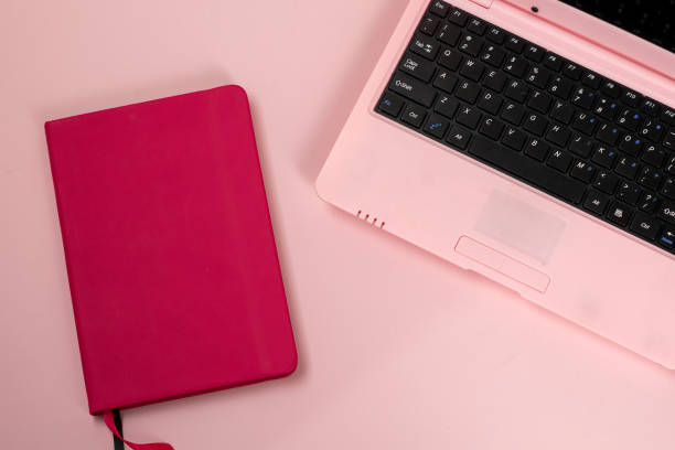 istock Pink laptop with pink notebook on pink background, feminine workplace 1998569141
