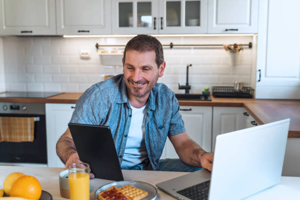 istock A man using laptop in the morning at the kitchen table  while having breakfast. 1998583069