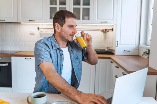 istock A man using laptop in the morning at the kitchen table  while having breakfast. 1998583070