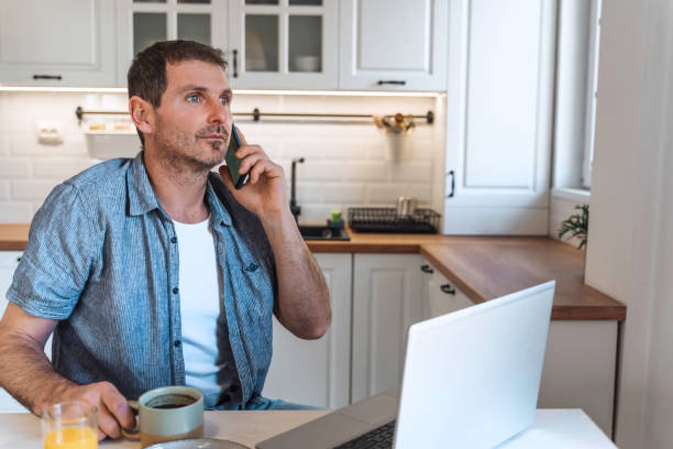 istock A man using laptop in the morning at the kitchen table  while having breakfast. 1998583071