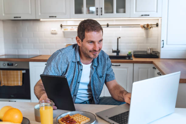 istock A man using laptop in the morning at the kitchen table  while having breakfast. 1998583595