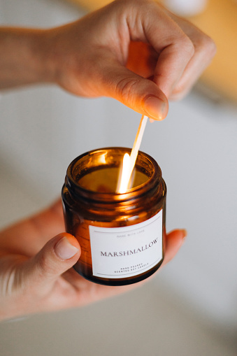 The simple yet profound act of lighting a candle at home. The delicate hands of a woman bring forth the warm glow, symbolizing hope, comfort, and introspection in the midst of life's moments