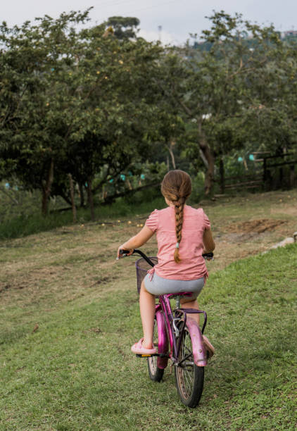 long-haired girl with her back turned while riding her bike in the park