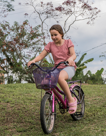 portrait of a girl playing in the park and smiling while riding her bike.