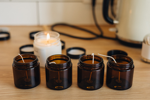 This scene showcases the careful preparation for homemade candle making, with glass jars neatly arranged and ready to receive the hot melted wax