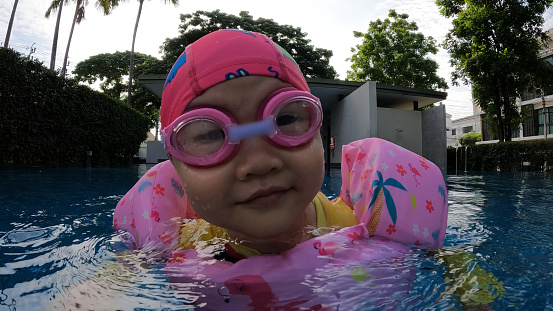 Asian girl in a swimsuit swims in the pool.