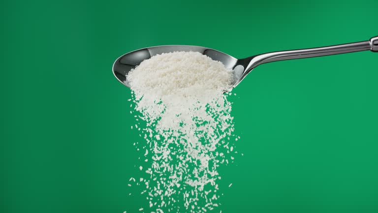 Super slow motion pile of grated white coconut shavings falling from a spoon