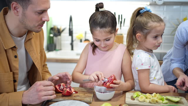 Parents with daughters making healthy breakfast with pomegrande at the modern kitchen
