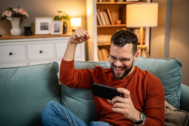 istock A man playing video games on his smartphone, visibly excited and happy because he is winning, rejoices 1998643768