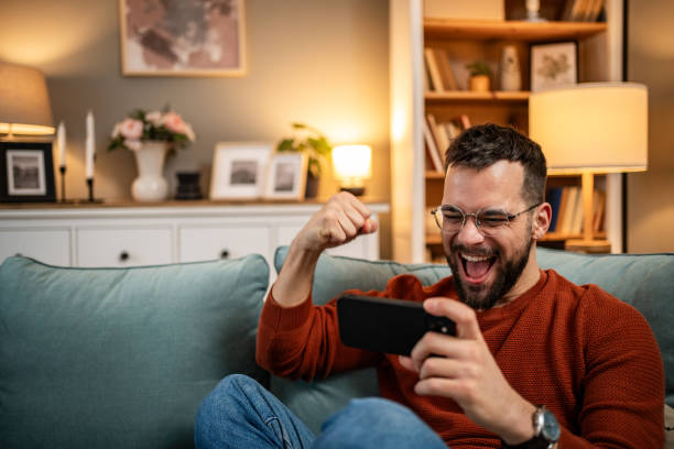istock A man playing video games on his smartphone, visibly excited and happy because he is winning, rejoices 1998643773