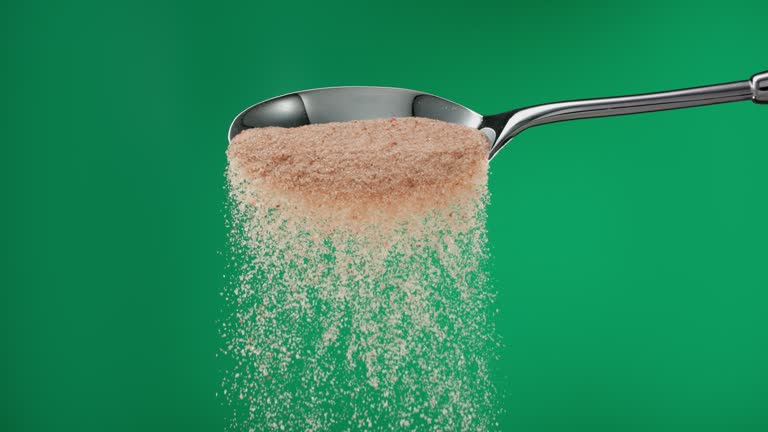 Super slow motion pile of brown ground sugar falling from a spoon