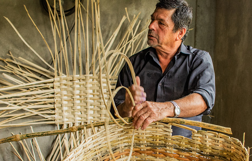 portrait of a craftsman at work in his workshop where he makes handmade baskets from natural resources.