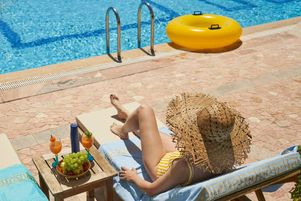 istock Fashionable woman sitting by the pool on the empty deck 1998682972