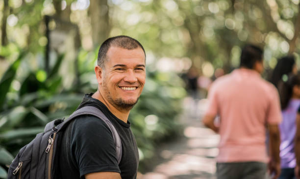 istock Portrait of a man smiling while strolling through a public park. 1998685132