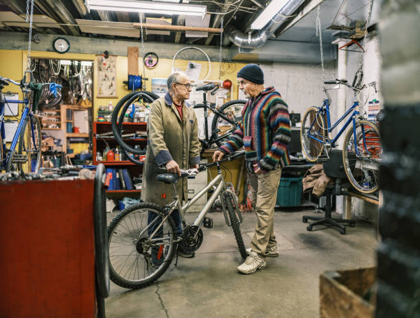 Two Senior men talking in bicycle shop. Shop owner interacting with customer about the bicycle repair. Both dressed in casual clothes. Interior of bicycle shop in Hamilton, Canada.