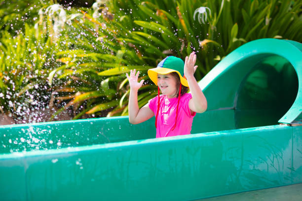 Kids on water slide in aqua park. Children having fun on water slides on family summer vacation in tropical resort. Amusement park with wet playground for young child and baby.