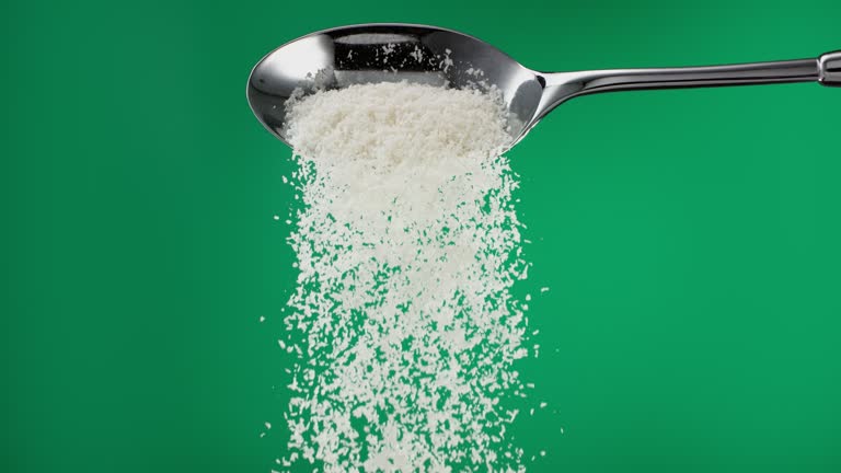 Super slow motion pile of grated coconut flakes falling from a spoon