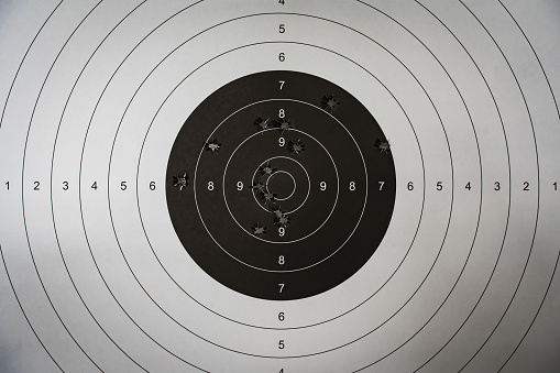 A paper target for shooting with holes from 9mm pistol bullets in the center, close-up photo. High quality photo