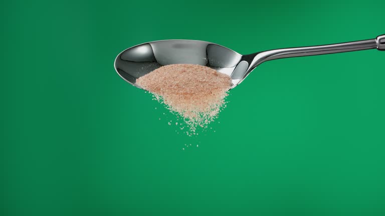 Super slow motion pile of brown sugar falling from a metal spoon