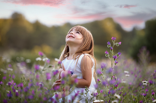 Adorable smiling little girl in princess dress sitting on grass outdoor