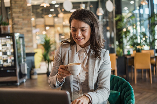 A modern business woman successfully integrates her professional obligations into her daily life, she ends her business obligations at the cafeteria where she enjoys a good coffee.