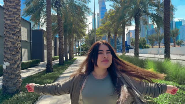 happy girl with long hair spins in the city with a view of high-rise buildings. High quality FullHD footage