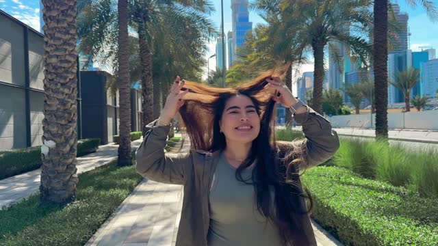happy girl with long hair spins in the city with a view of high-rise buildings. High quality FullHD footage
