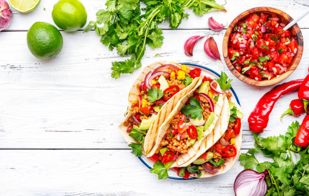 istock Tacos with ground beef, sweet corn, red beans, tomato salsa sauce and red onion in corn tortillas on plate. Mexican cuisine. Taco party menu. White table background, top view 1998902424