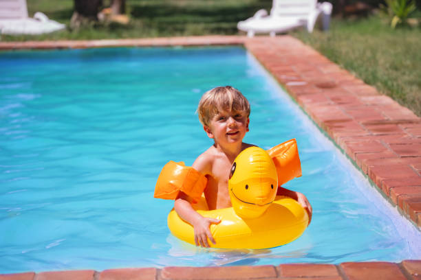 Blond haired boy with diving mask and swimming ring in the pool