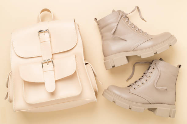 istock Beige trendy boots and backpack on color background, top view. 1998943563