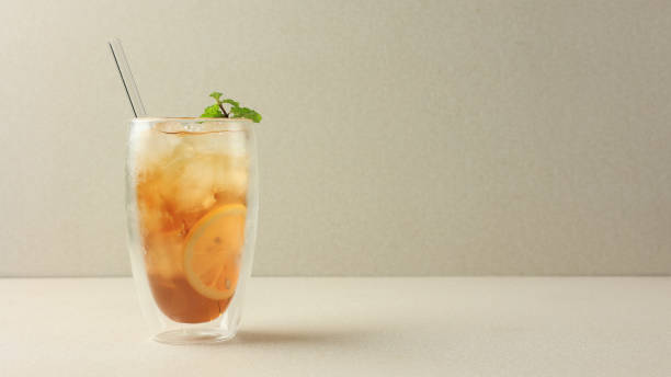 istock ICed Lemon Tea on Cream Background with Glass Straw 1999016383