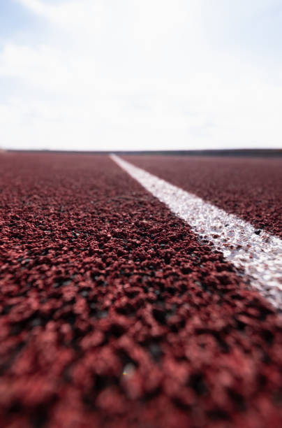 Close-up of a white lane line on a red running track, with a blurred background.