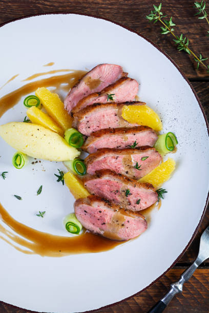istock Roast duck fillet with mashed potato and orange sauce on wooden background 1999046552
