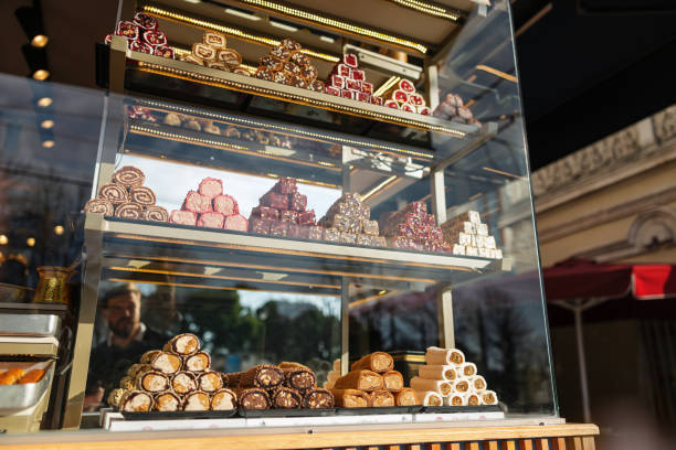 Colorful array of traditional Turkish delights showcased in a glass display at a sweet shop in Istanbul, with reflections of city life.