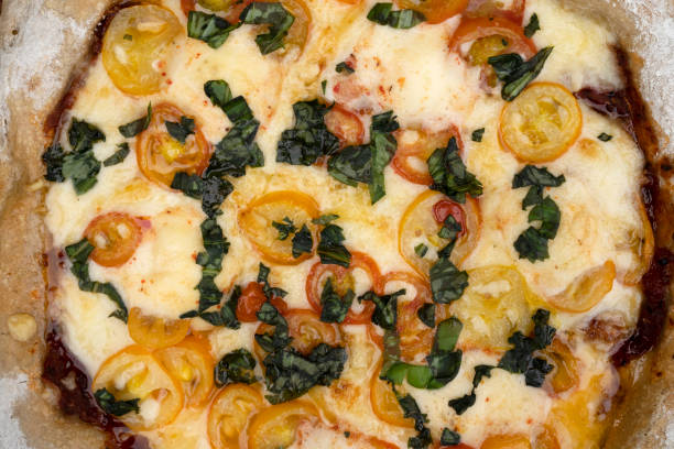 Pizza background. Closeup view of a pizza with mozzarella and provolone cheese, garlic and cherry tomatoes.