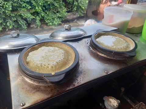 sweet martabak being cooked on a baking sheet, a snack cart on the side of the road