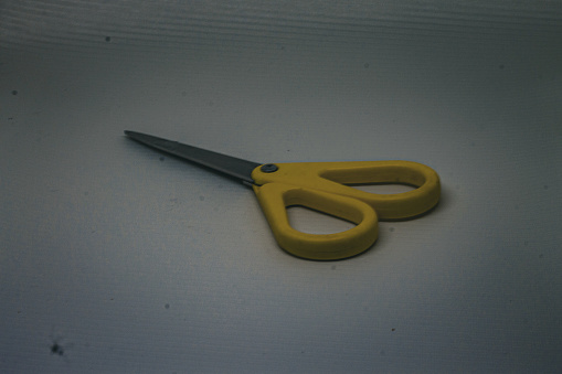 Yellow scissors on a white backdrop.