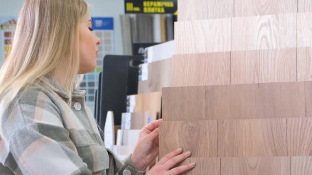 A female customer chooses linoleum in an interior store. Apartment renovation concept