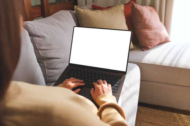 istock Mockup image of a woman working and typing on laptop computer with blank screen while sitting on sofa at home 1999218810