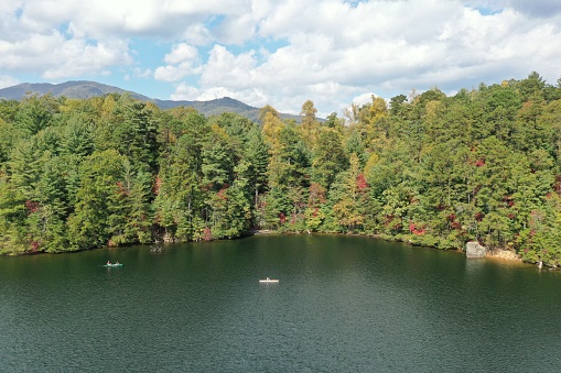 Aerial view of three young women canoeing and kayaking on Lake Santeetlah, North Carolina in autumn.