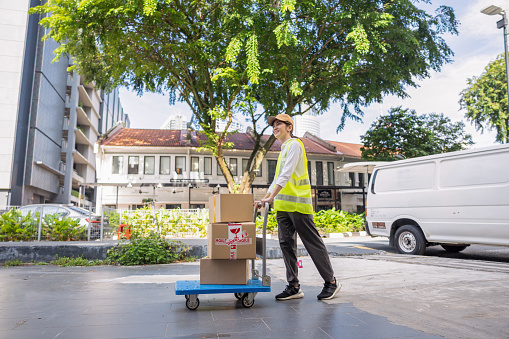 Delivery woman pushing cart with cardboard boxes