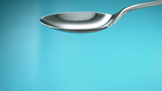 Empty spoon turning to spill out the contents. Cut out on blue screen