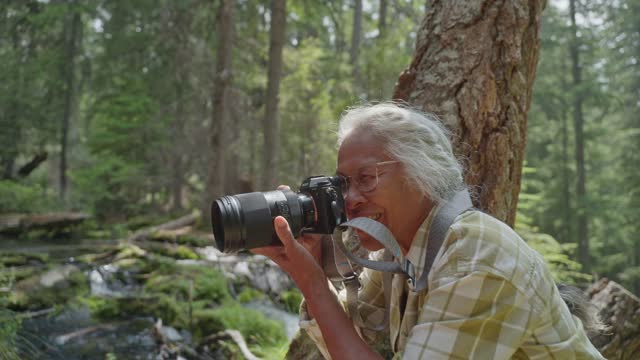 Active senior woman taking photographs while hiking in nature