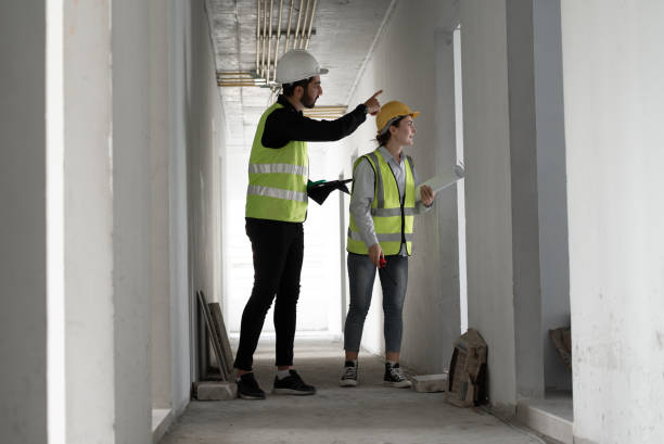 istock Caucasian engineer man and woman working with tablet computer and paper work in building at construction site 1999342814
