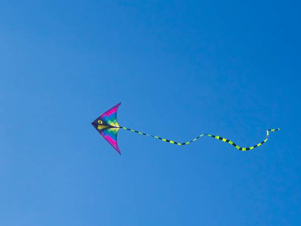 istock Brightly colored kite flies in clear blue sky 1999346575
