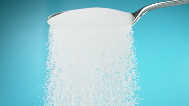 Super slow motion white sugar falling from a metal spoon