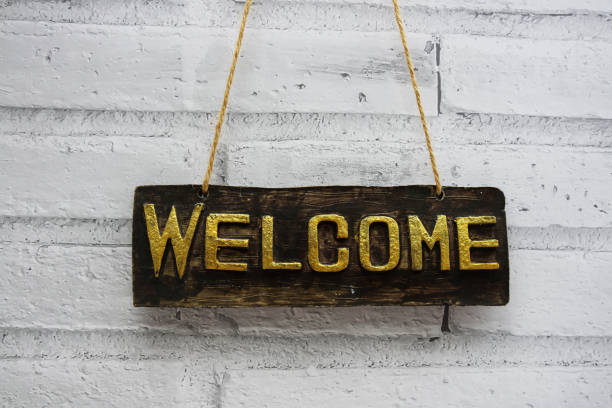 istock Welcome sign hanging with rope on white brick wall background 1999385672