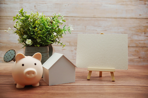 Piggy bank and house model on wooden background, Business investment and real estate concept