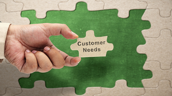 Business hand holding pieces of a jigsaw puzzle with customer needs text. Business and marketing concept
